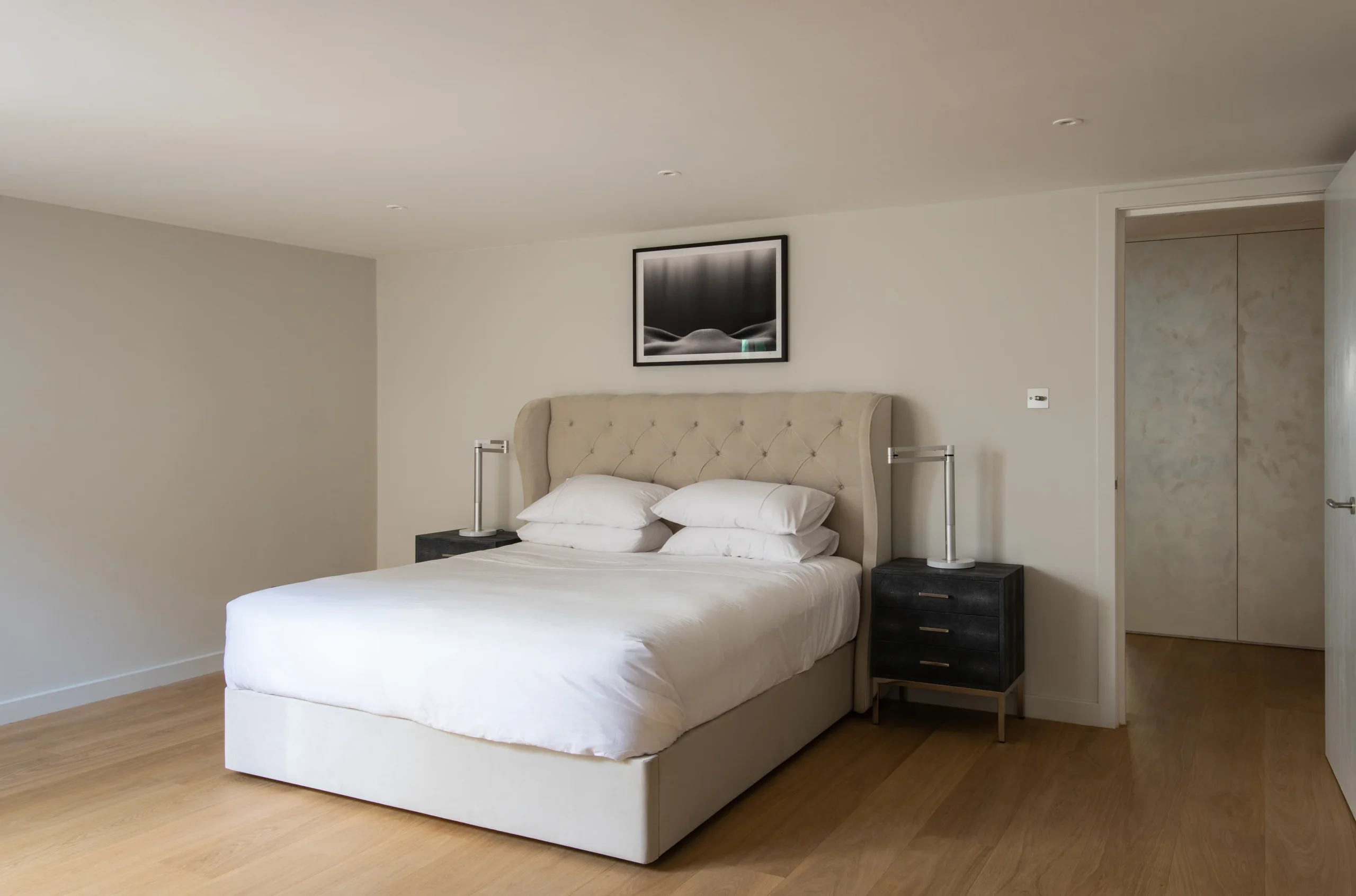 Bedroom with upholstered bed, oak floor and fitted storage