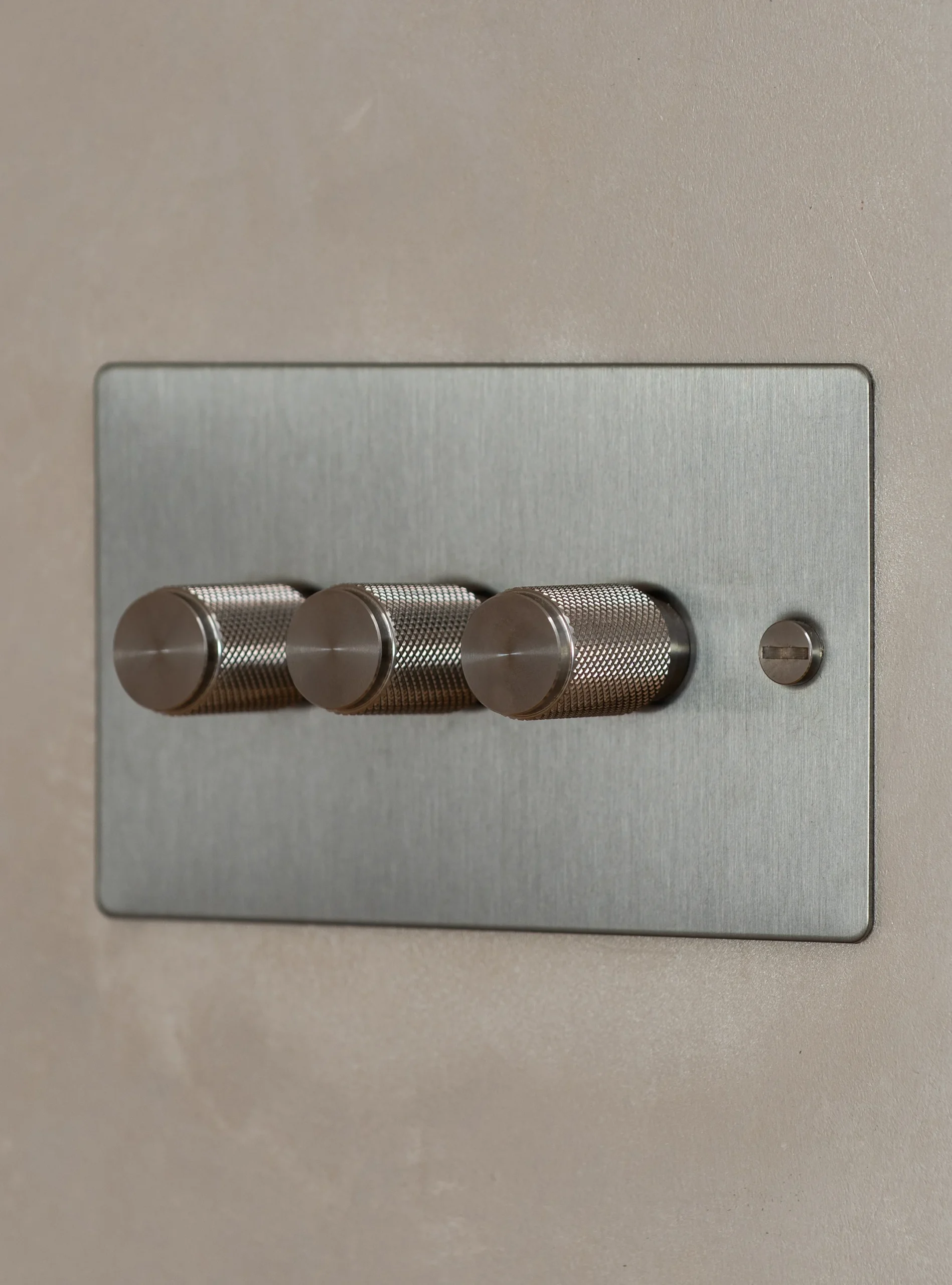 Brushed steel dimmer switch plate on a polished plaster wall