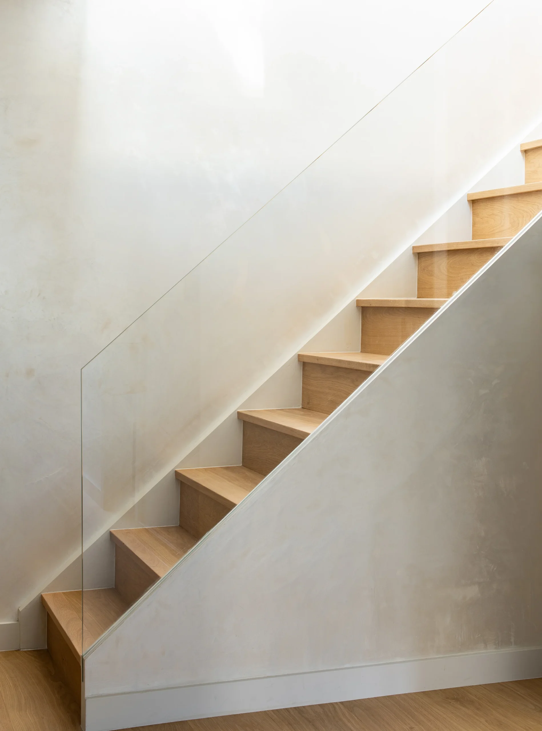 Oak stair treads beside a frameless glass balustrade