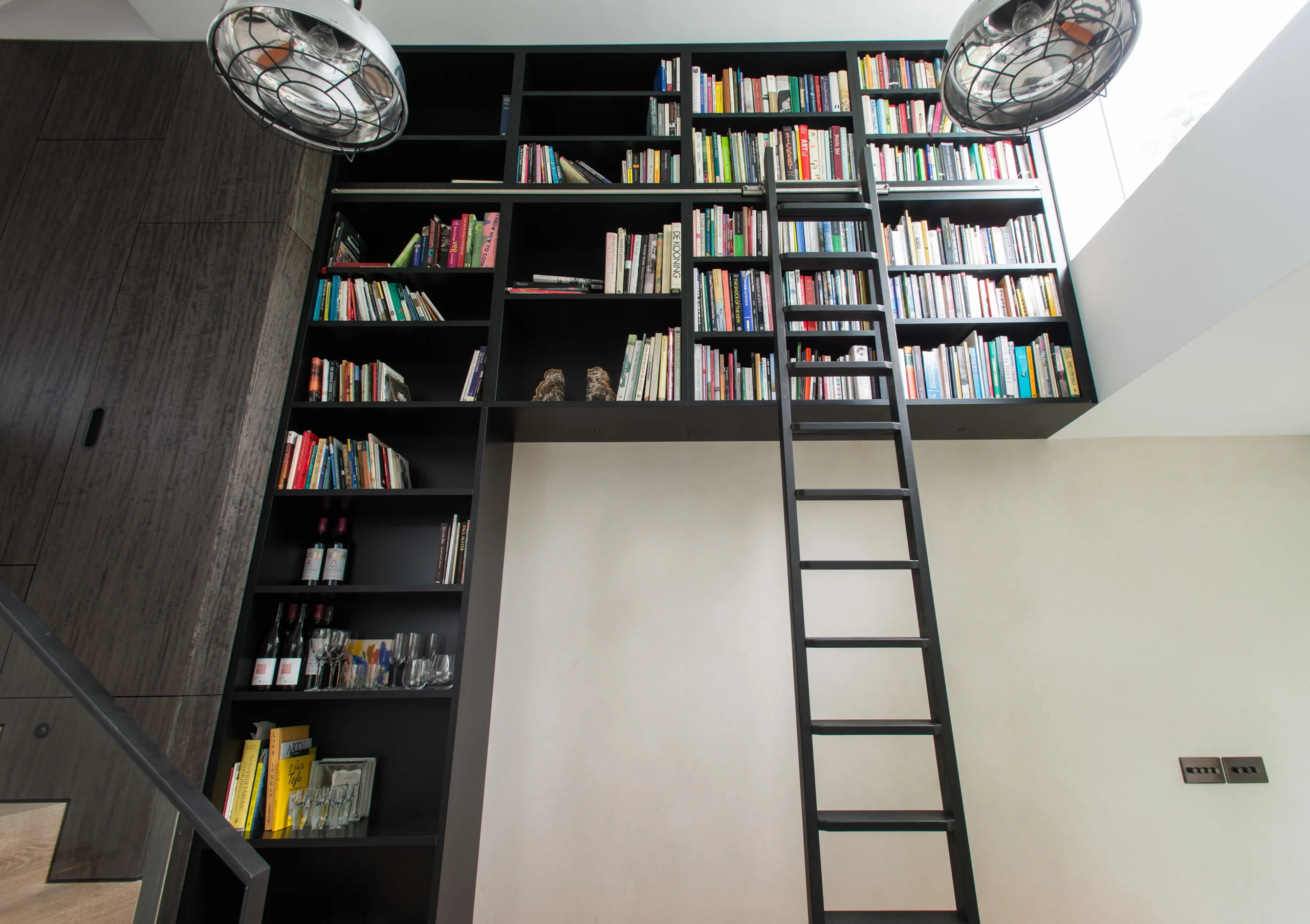 Camden_12_3840px Double-height black joinery library with a rolling ladder rising past the mezzanine