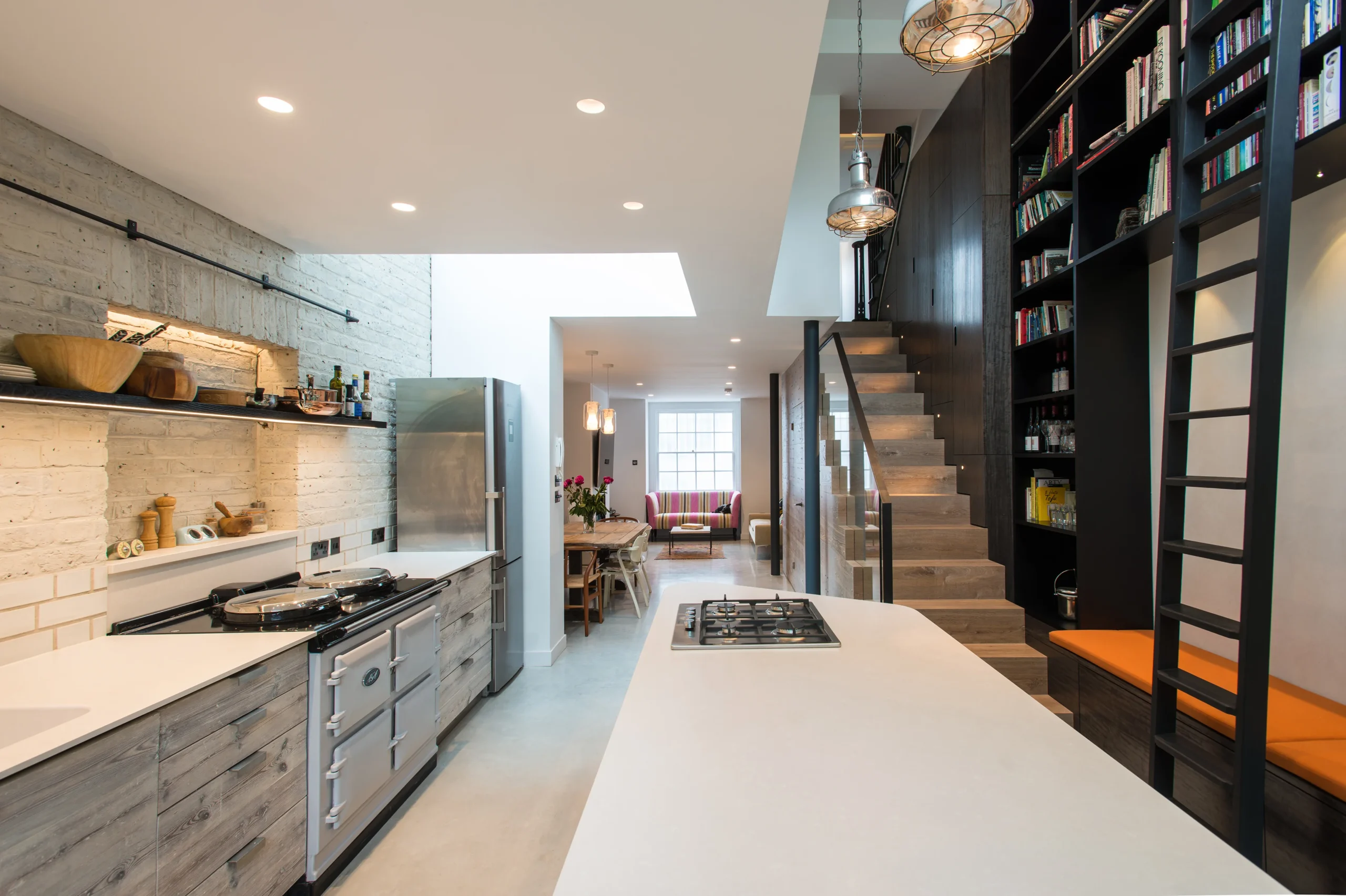 Camden_5_3840px Lower ground floor extension in Camden with a long kitchen along whitewashed brick, polished concrete floor and double-height library wall