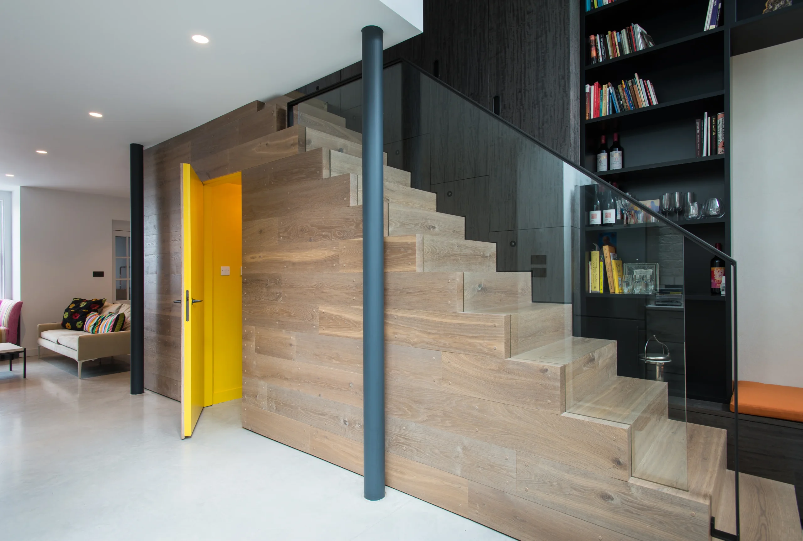 Camden_6_3840px Pale oak staircase with glass balustrade beside the library, yellow flush door and exposed steel column