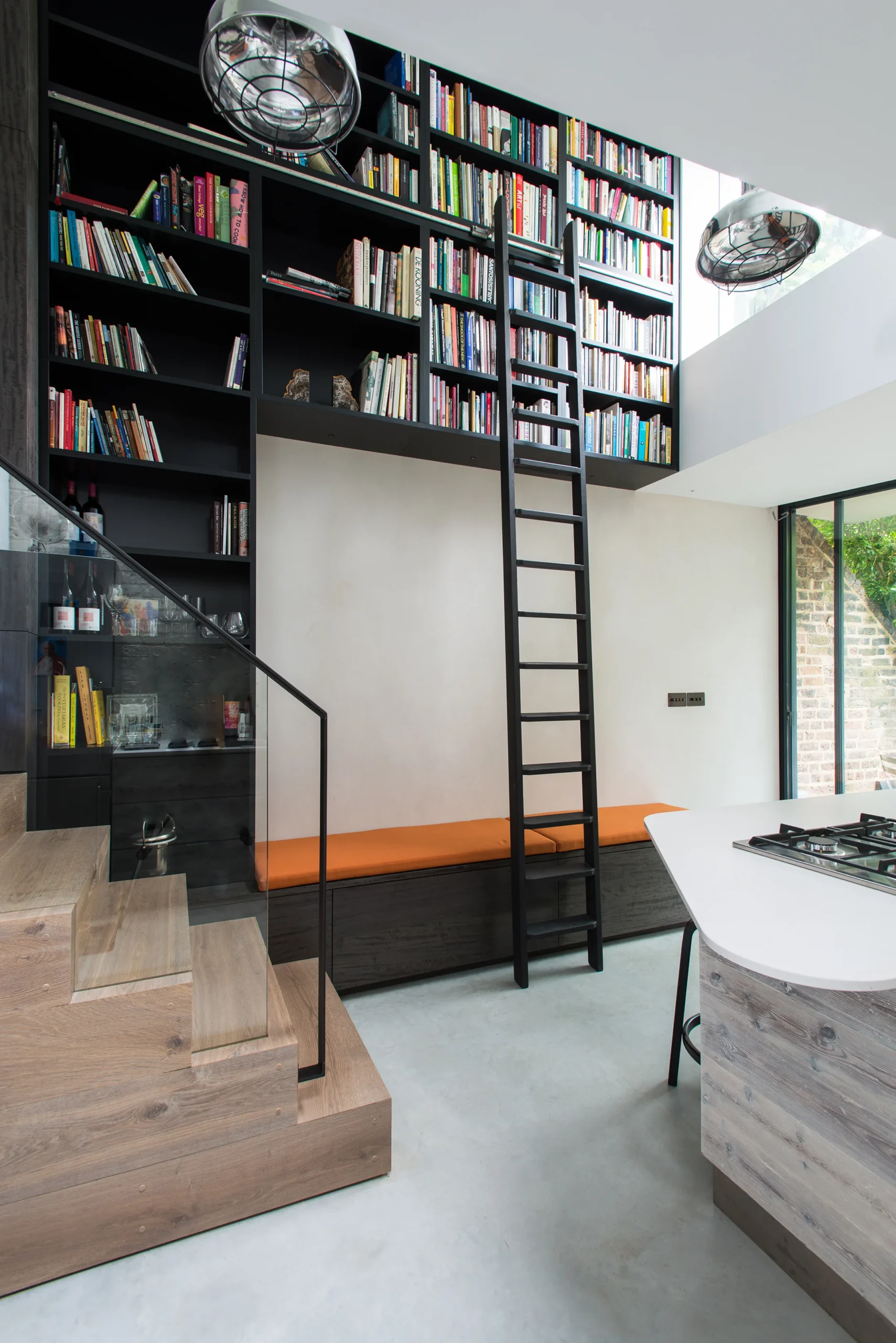 Camden_7_2160px Library wall and ladder above an orange built-in bench at the foot of the oak staircase