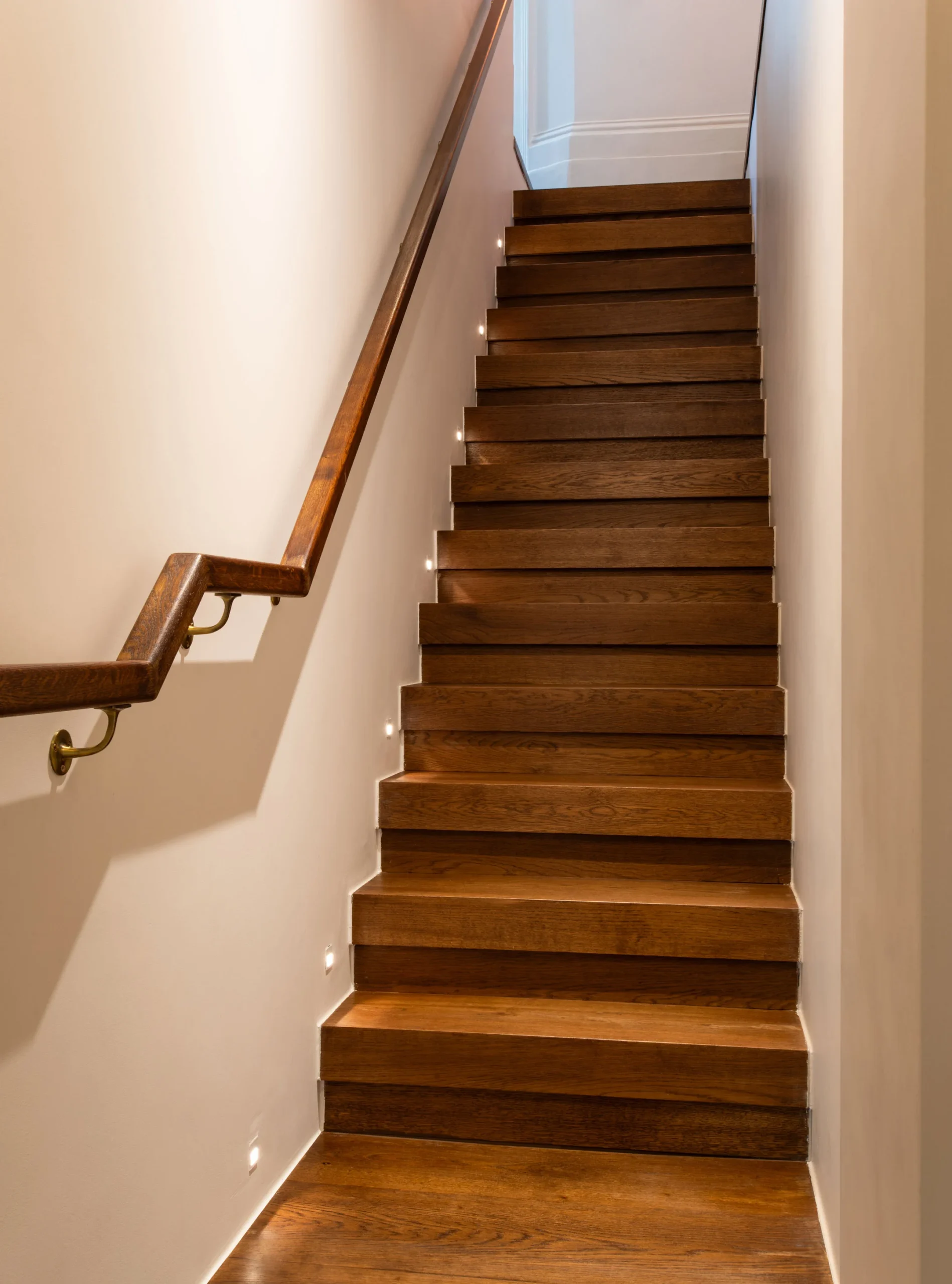 Oak staircase with slim timber handrail leading down to the basement bedrooms