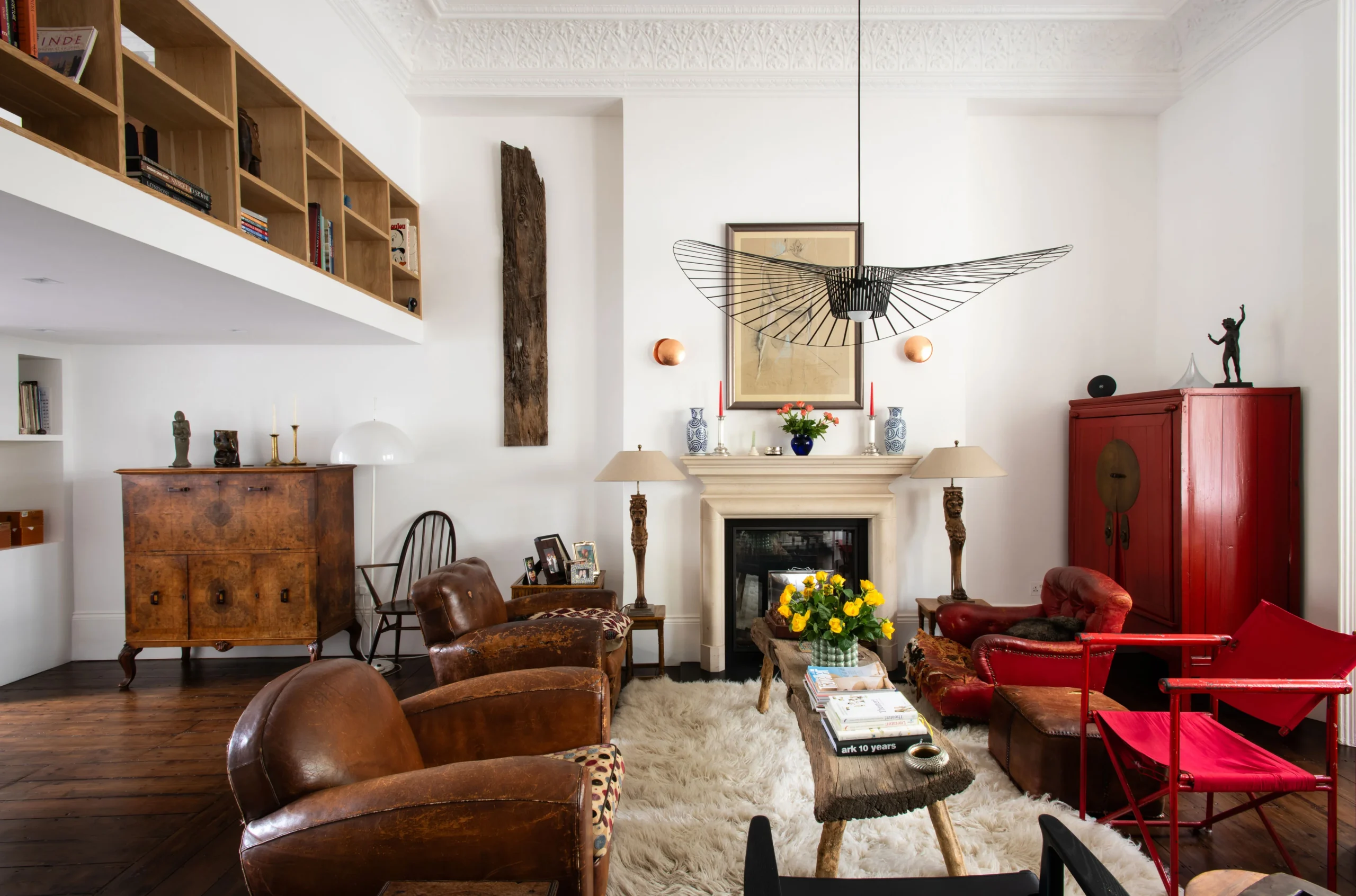 Double-height reception in a Kensington house renovation with mezzanine study, oak shelving balustrade and period fireplace