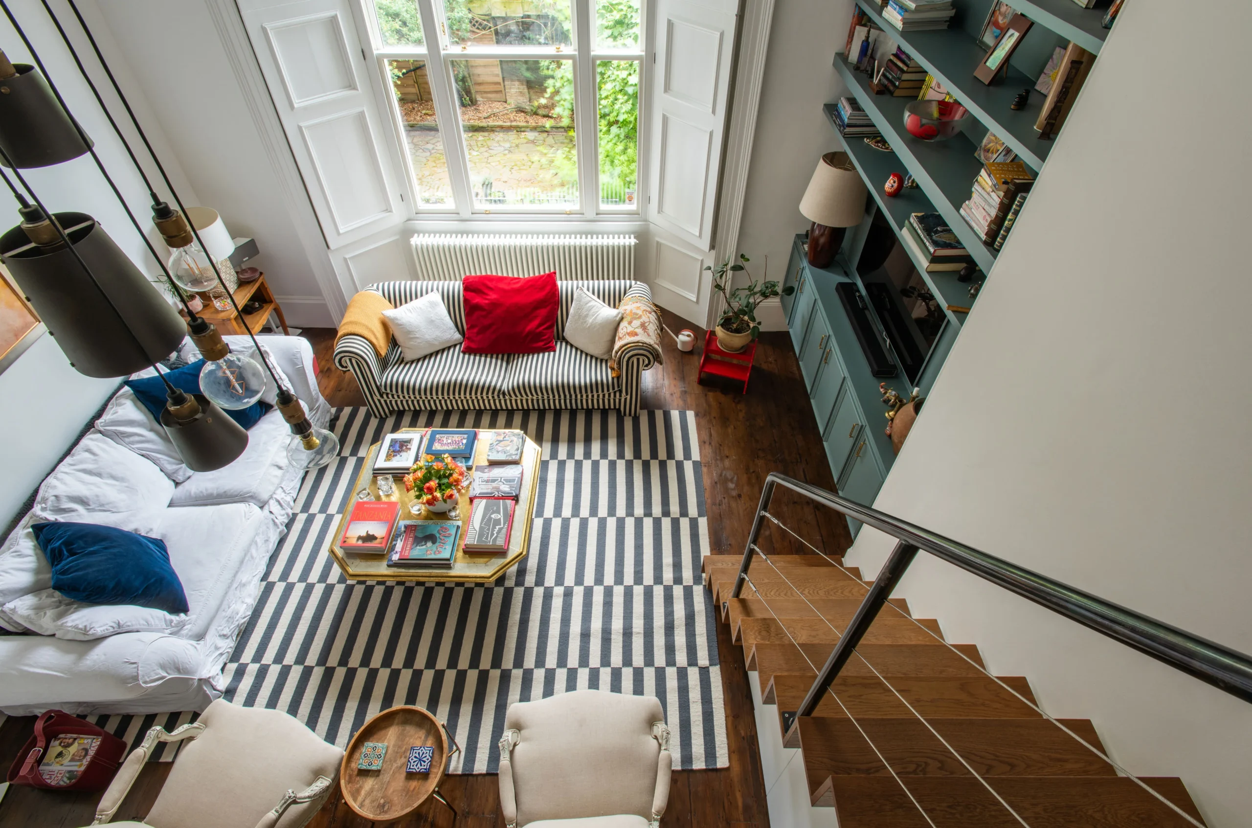 Living room seen from the mezzanine, with striped rug and teal fitted shelving