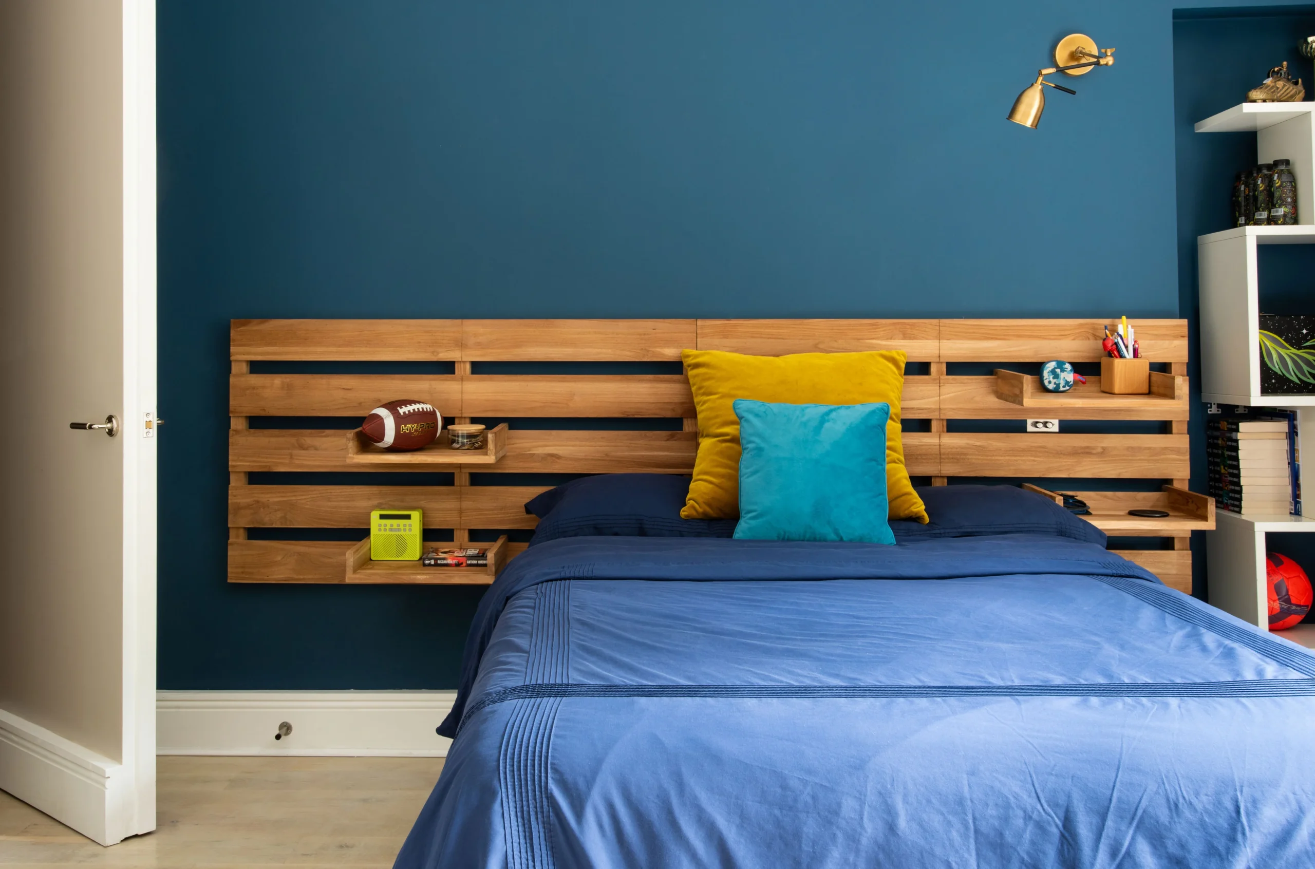 Bedroom with deep blue wall and reclaimed timber headboard shelf