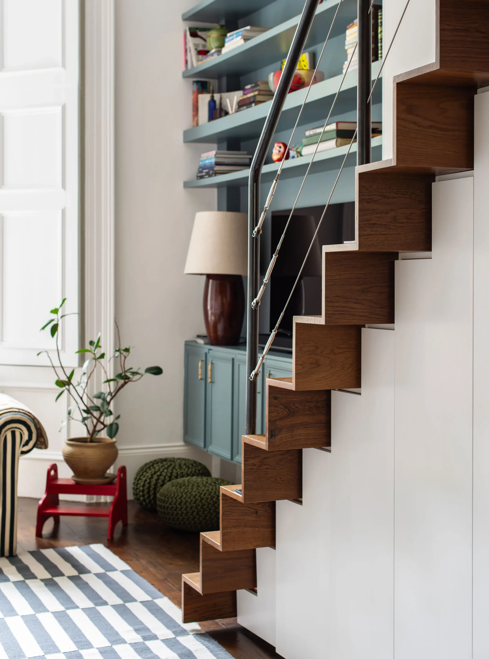 Alternating-tread oak staircase with black steel handrail rising to the mezzanine study