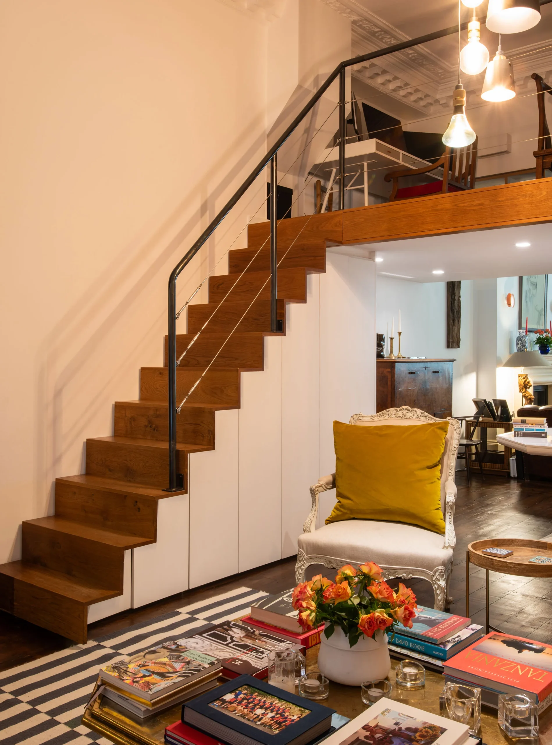Oak staircase to the mezzanine over concealed white storage joinery