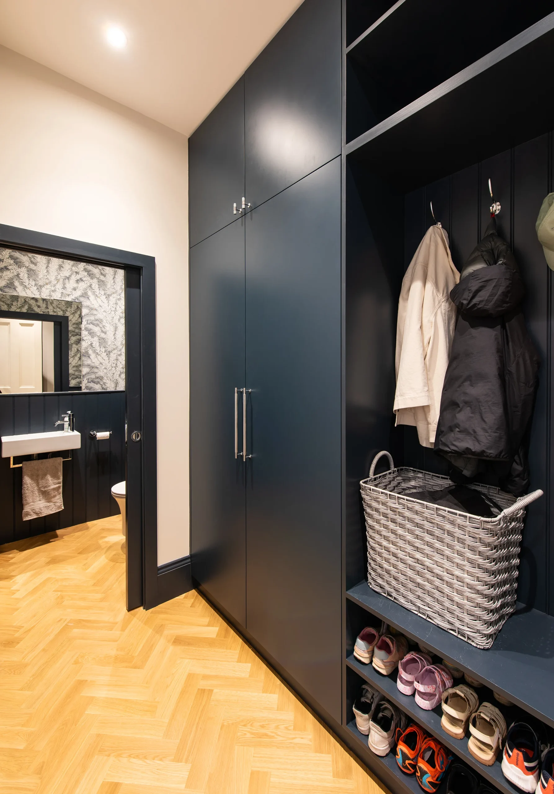 Hallway with dark fitted cloakroom storage and herringbone parquet floor
