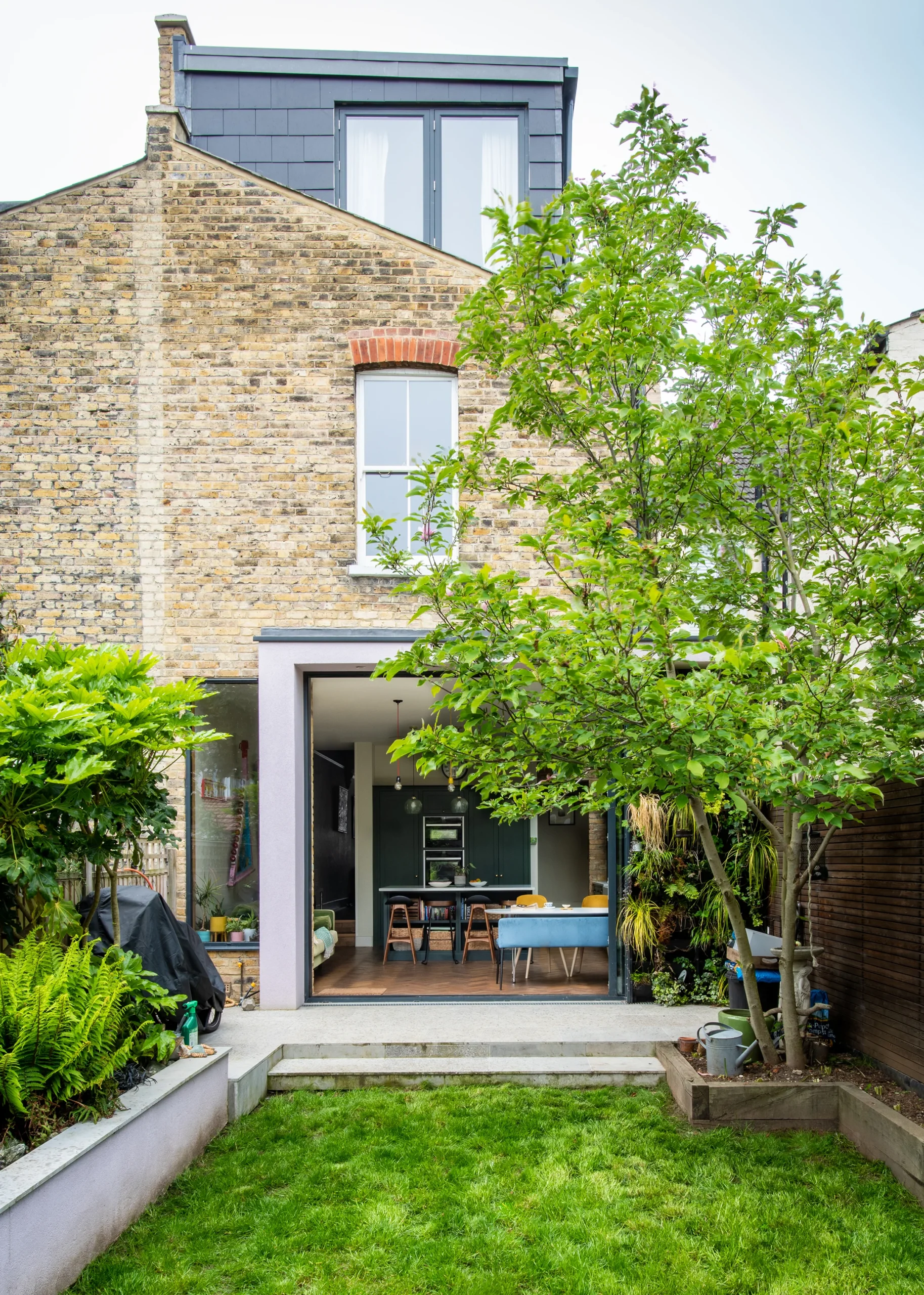 Rear garden view of a Victorian terrace with glazed side return extension and slate-clad rear dormer