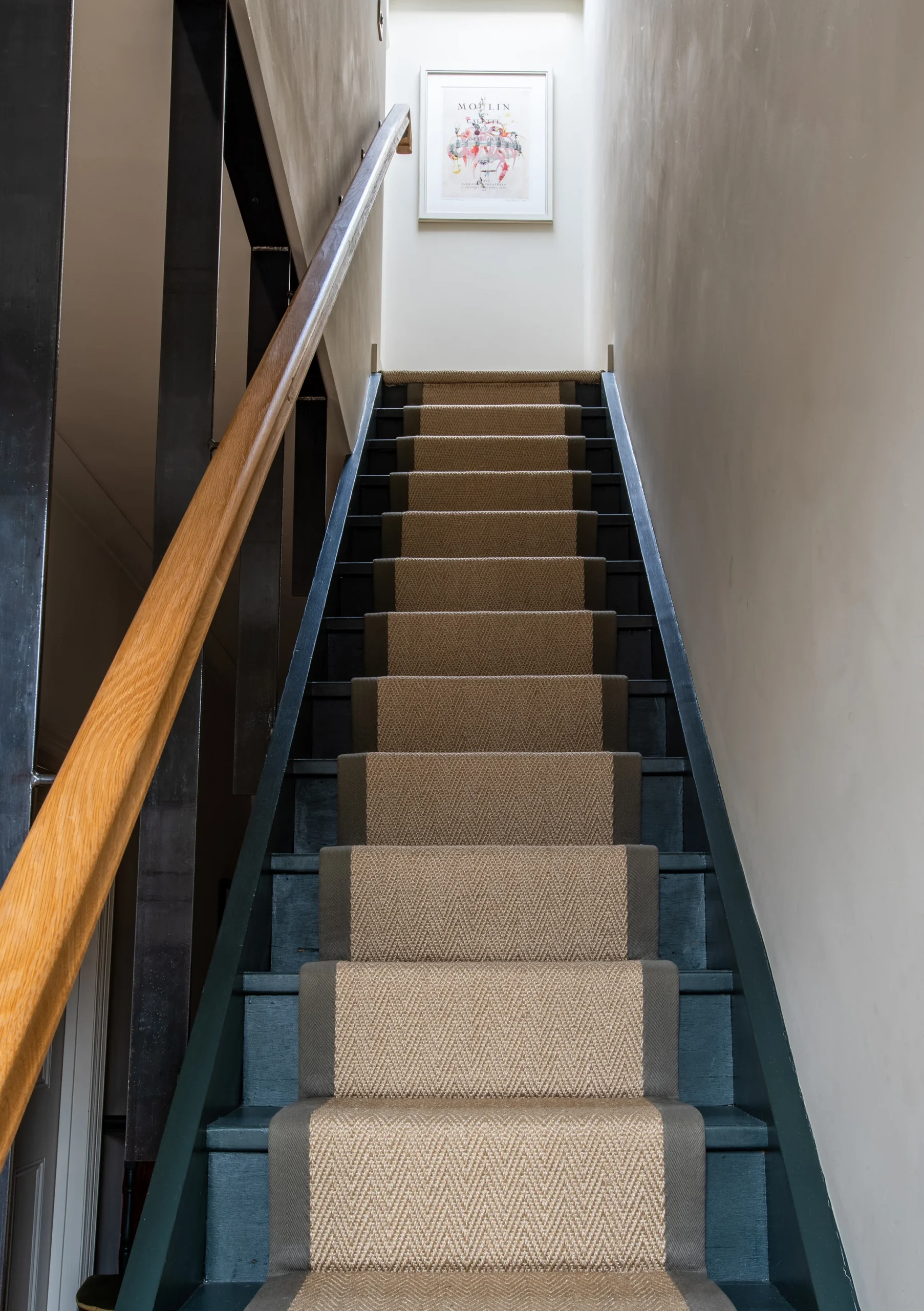 Narrow staircase with sisal runner, dark painted spindles and oak handrail