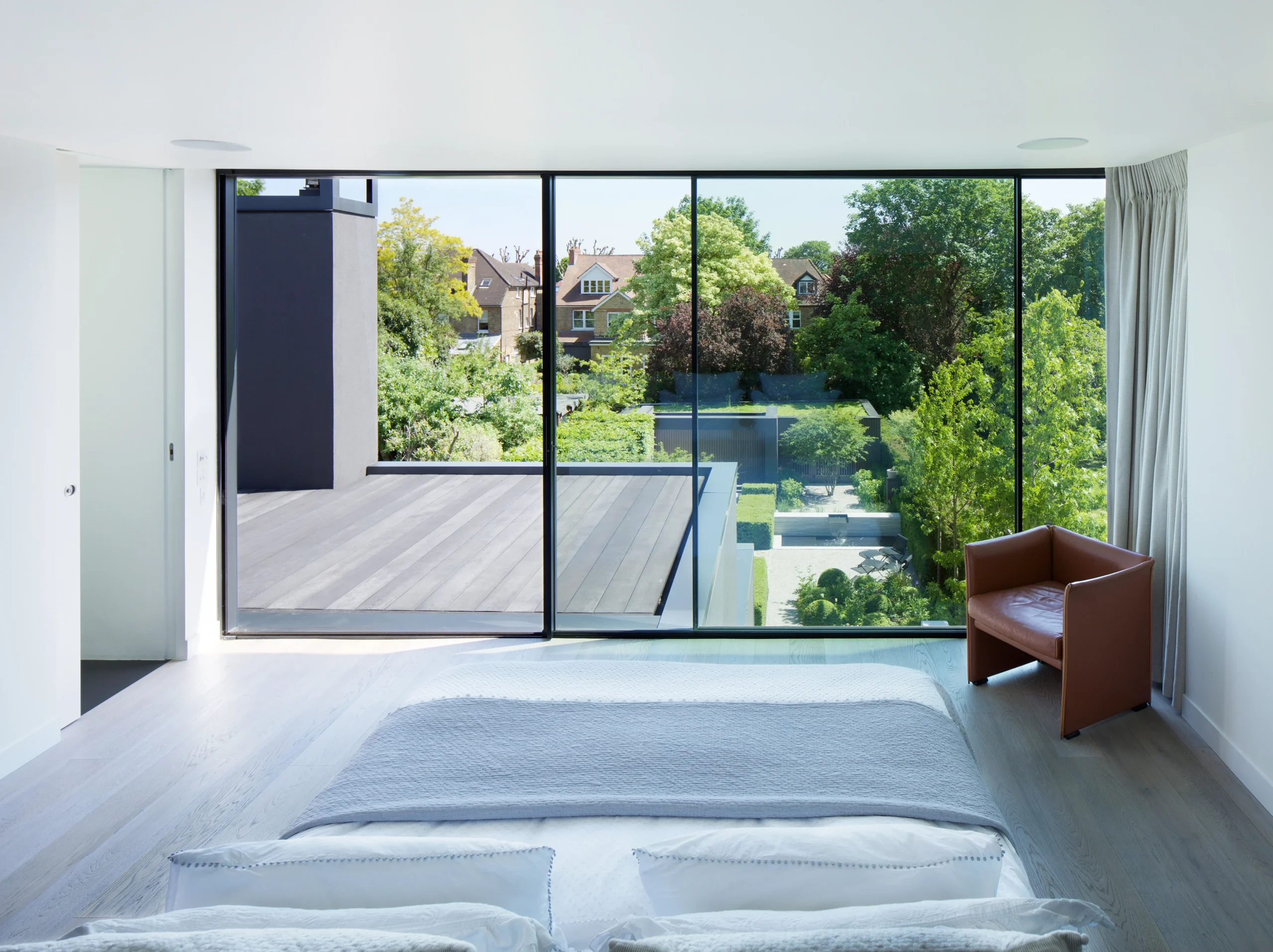 Bedroom opening onto a full-width glazed wall with a view over the garden