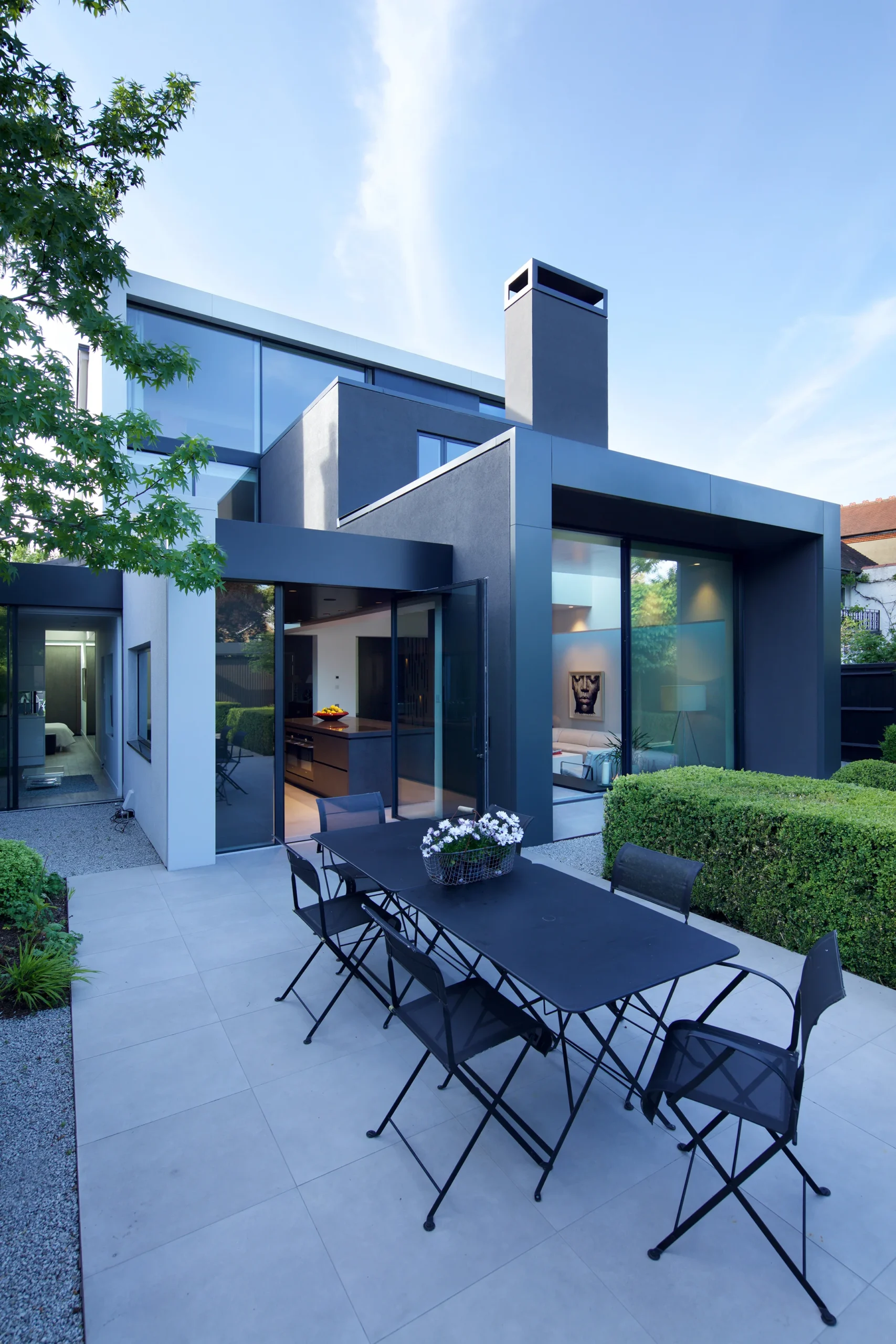 Rear terrace with outdoor dining beside the grey rendered extension and tall chimney block
