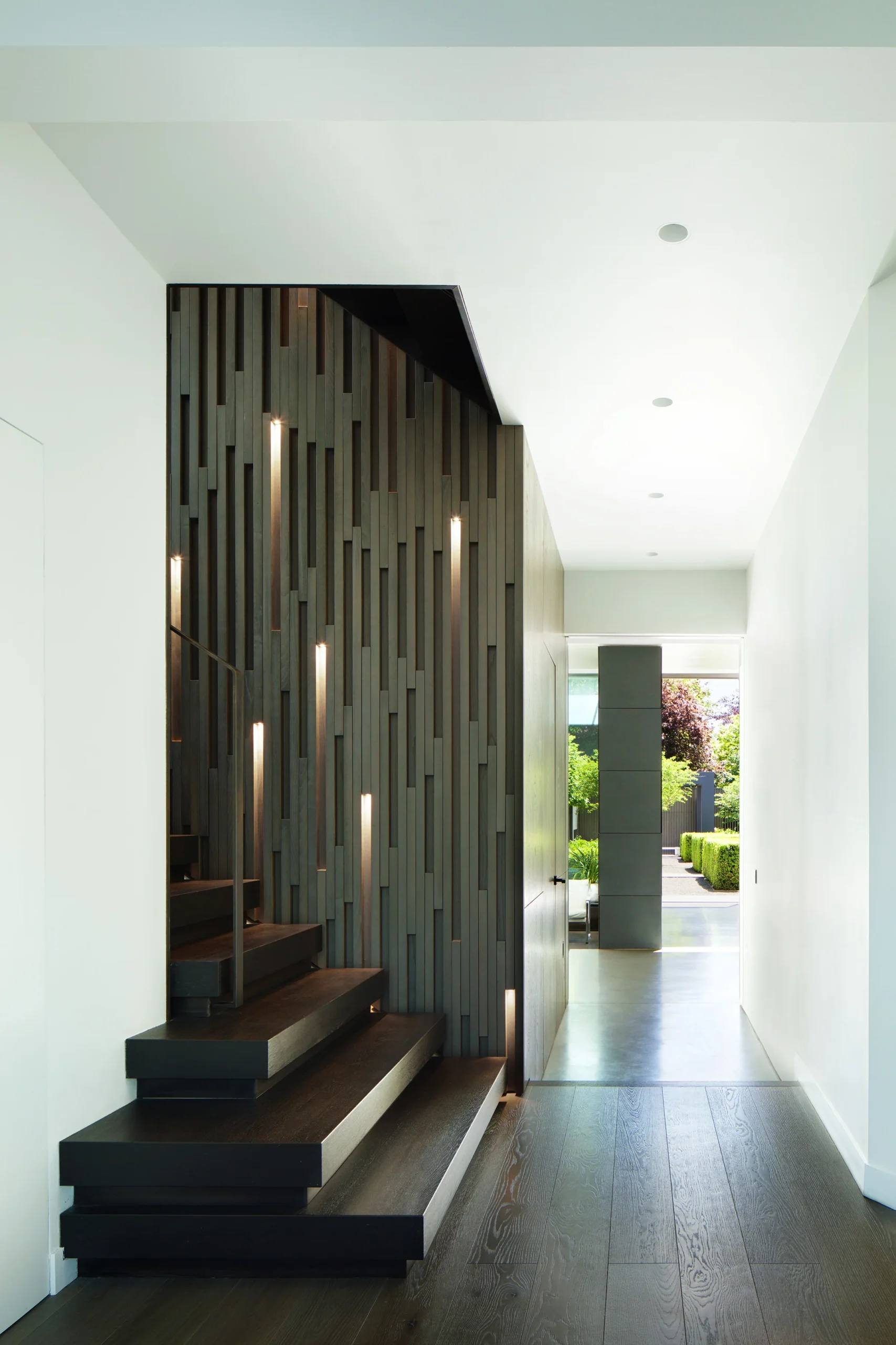 Hallway with a dark slatted feature wall and cantilevered timber stair treads
