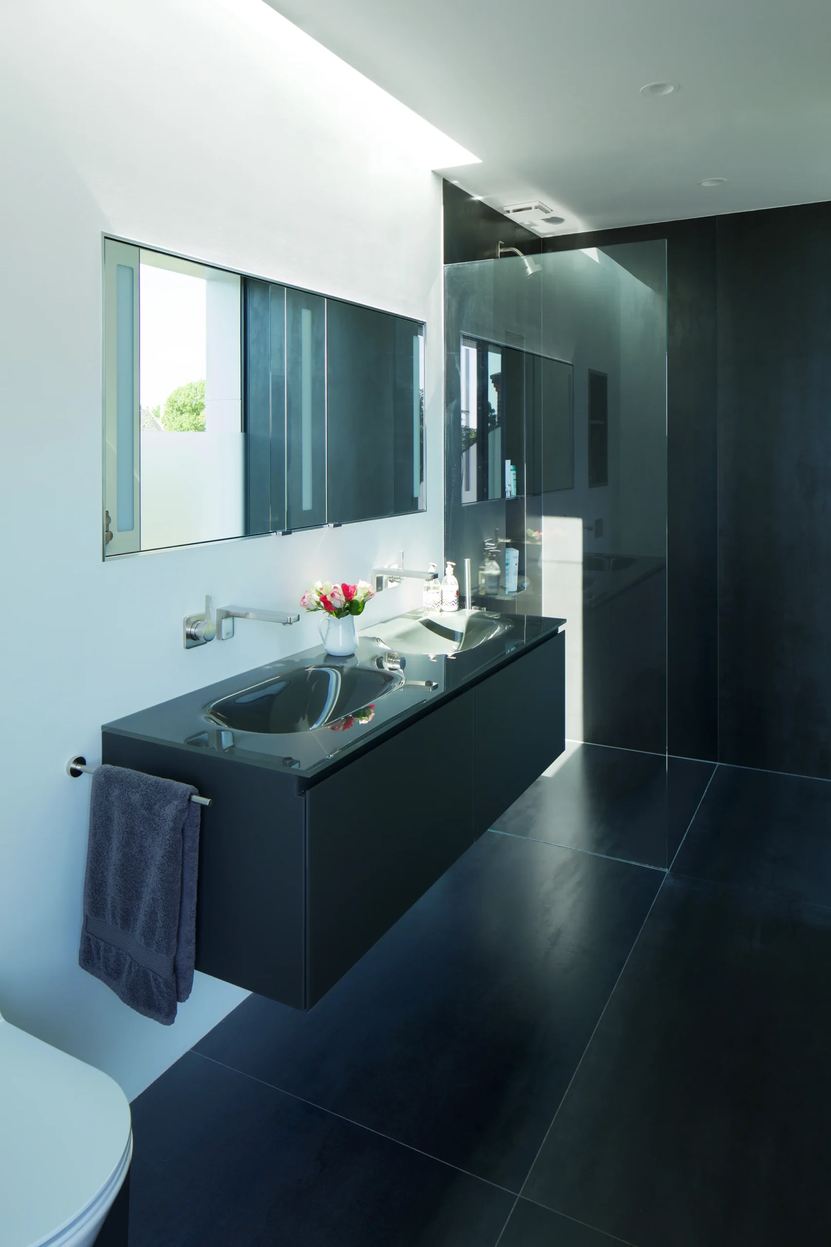 Bathroom with dark stone vanity, wall-mounted mirror and large-format floor tiles
