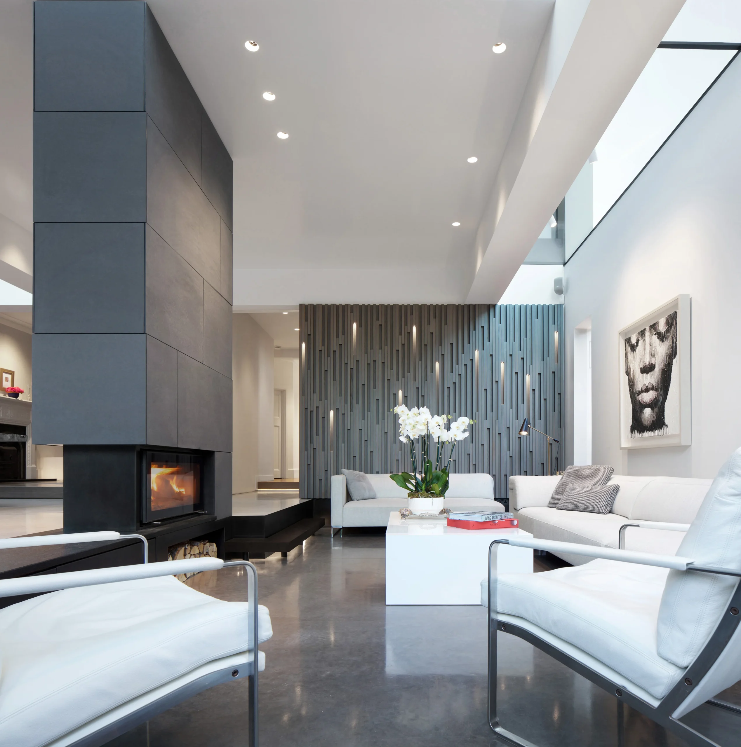 Double-height living room with grey stone fireplace, rooflight and white sofas