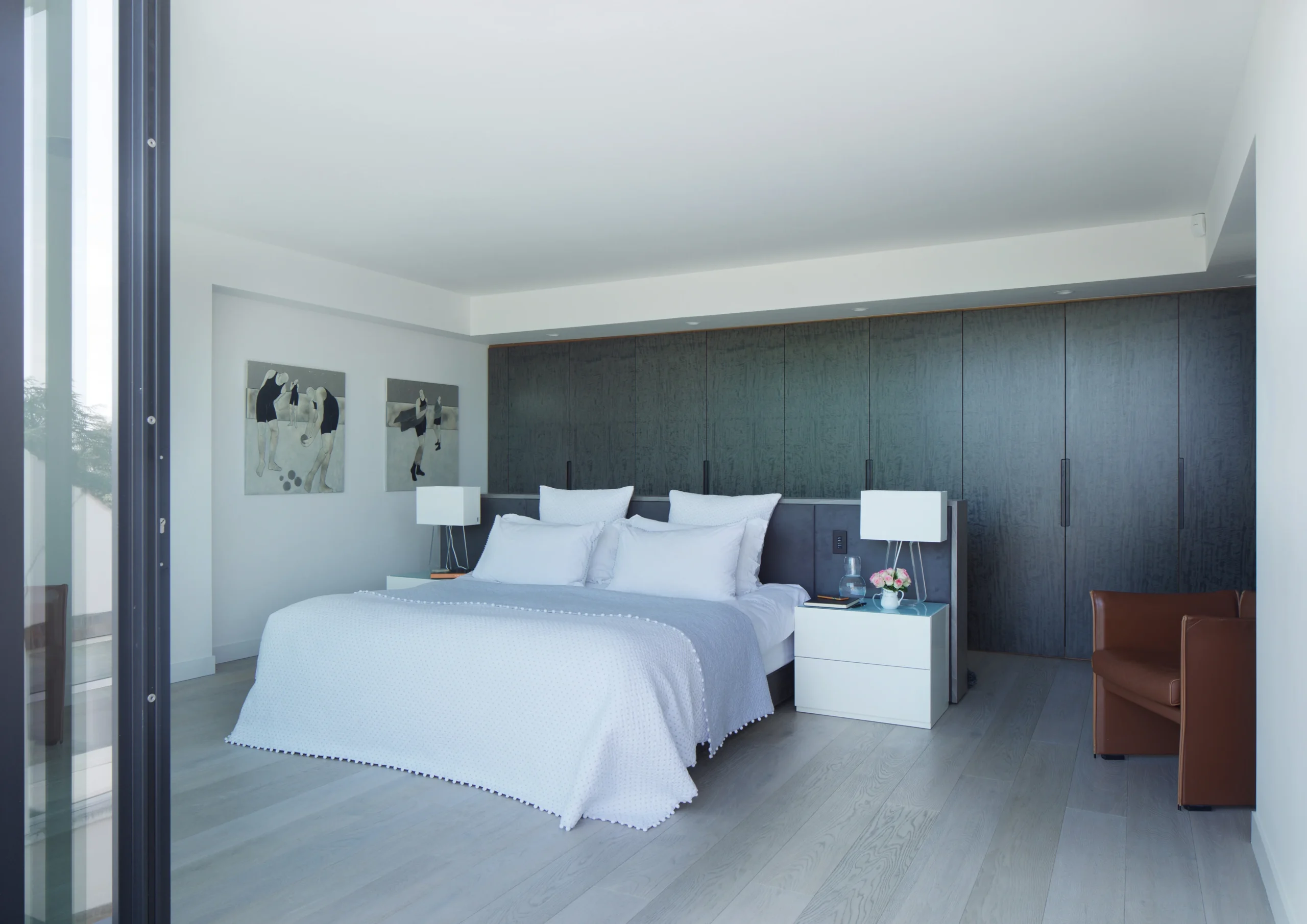 Bedroom with dark full-height fitted wardrobes and pale timber floor