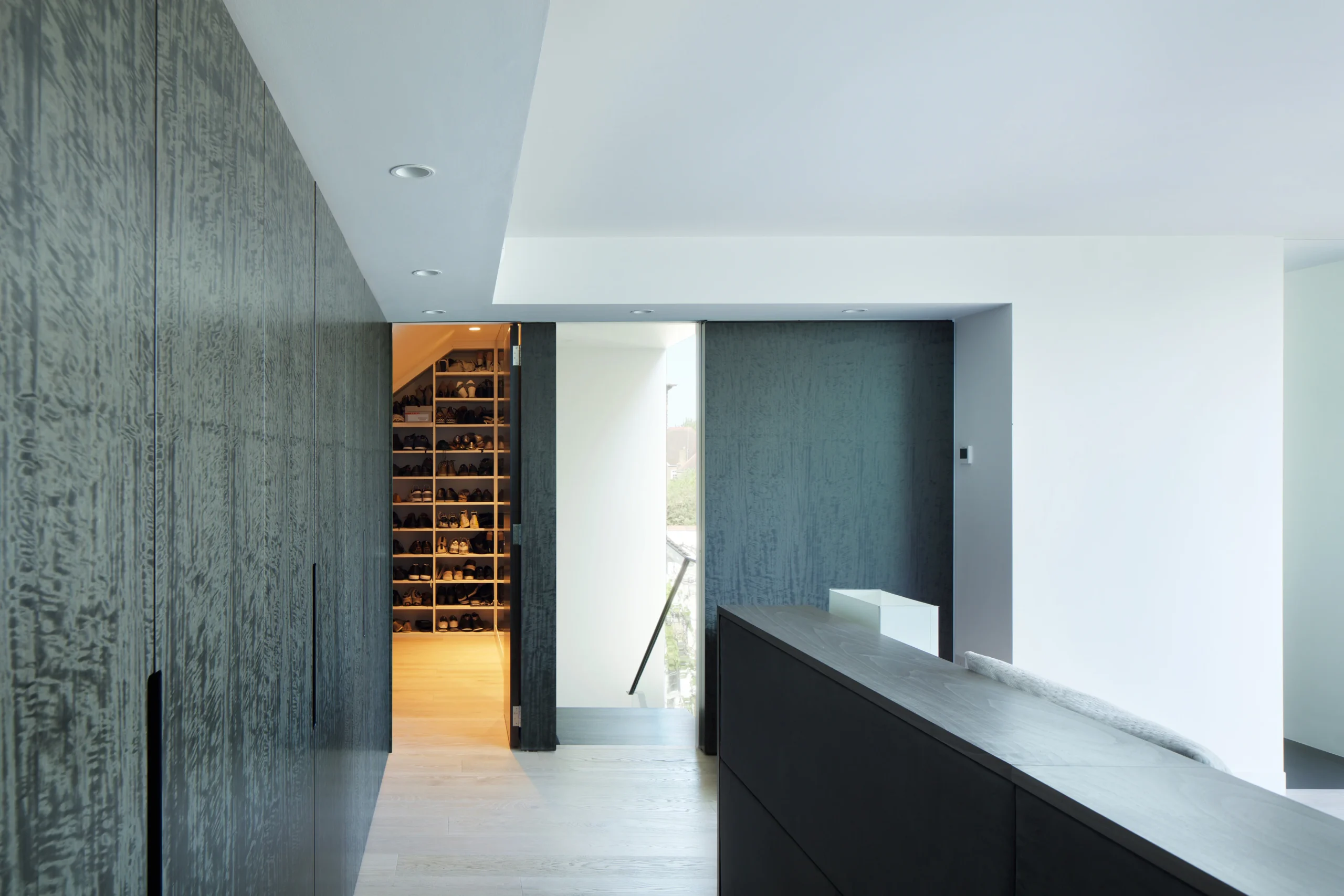 Dark timber-clad wall with a concealed door opening into a walk-in dressing room