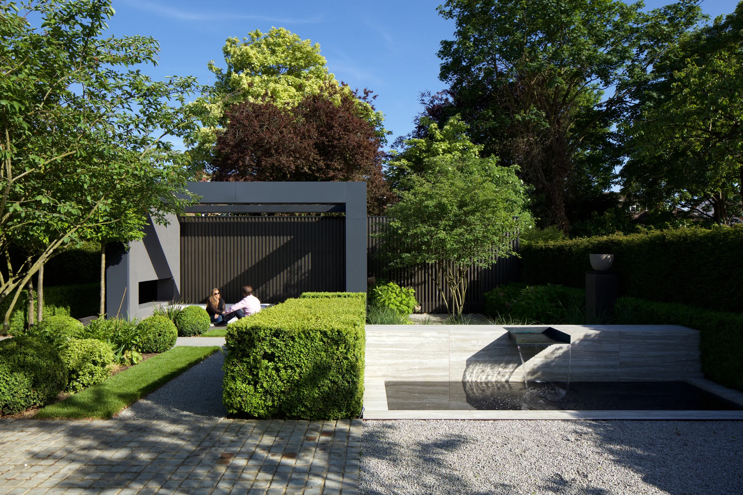 Landscaped rear garden with clipped box hedging, gravel and a garden room