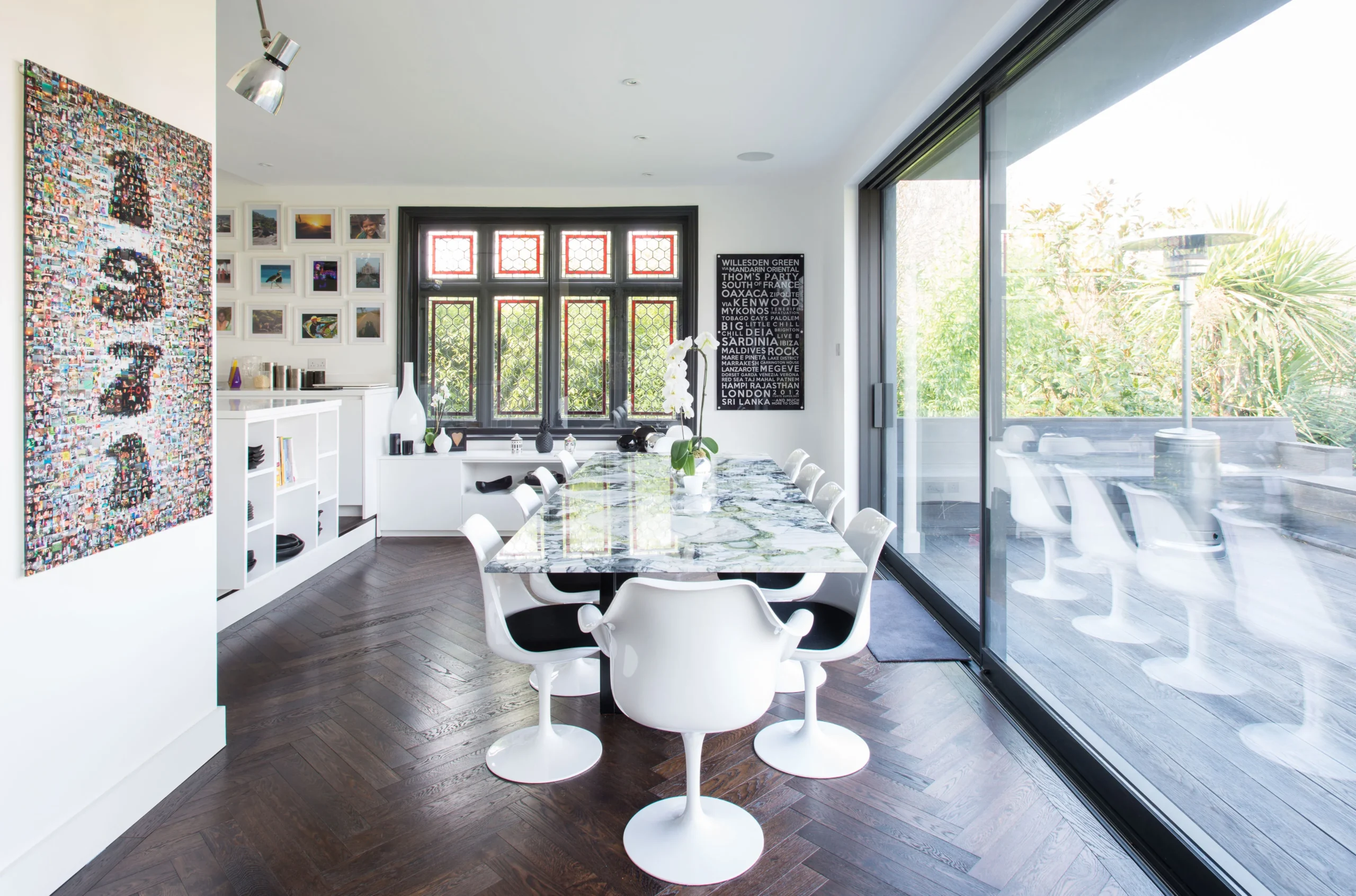 Dining area with marble-topped table and white tulip chairs beside full-height sliding doors