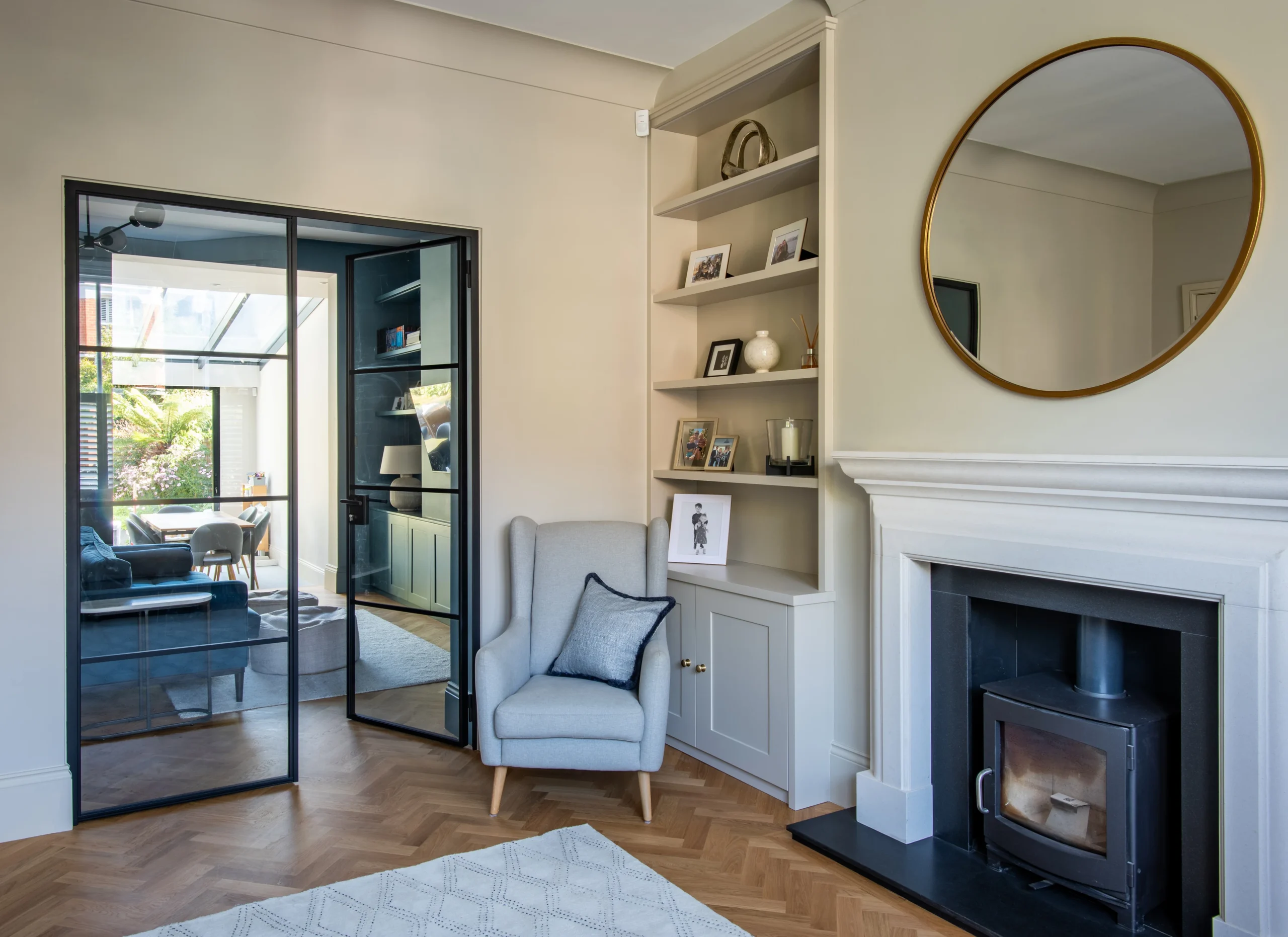 Front reception with wood burner, alcove shelving and crittall-style steel doors through to the kitchen extension